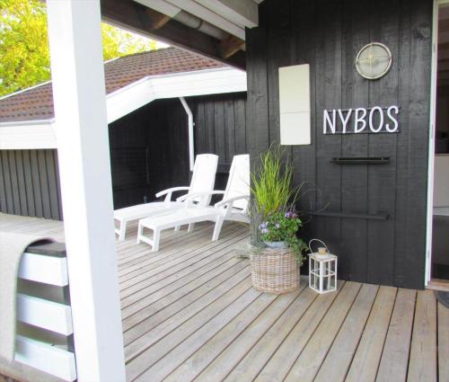 a wooden deck with white chairs and a nysbos sign at 8834-Glesborg-Hemming-Nielsens-Vej-11 in Glesborg
