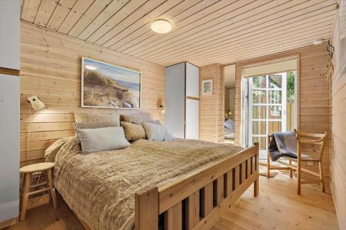 ein Schlafzimmer mit einem großen Bett und einer Holzwand in der Unterkunft 8538 Grenaa - Klitten 53 in Grenå