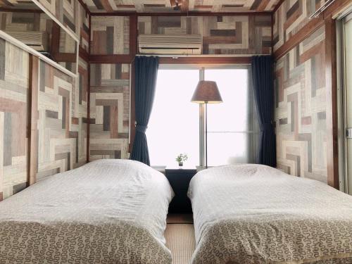 two twin beds in a room with a window at Haneda Artistic House in Tokyo