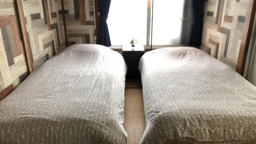 two twin beds in a room with a window at Haneda Artistic House in Tokyo