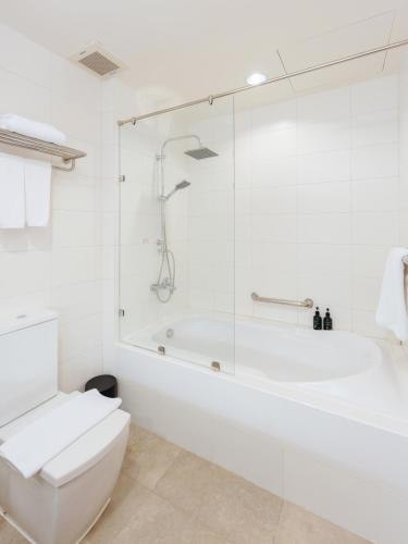 a white bathroom with a tub and a toilet at The Kaset, Hua Hin in Hua Hin