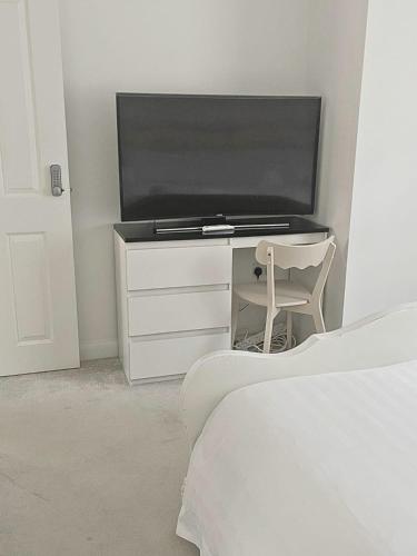 a bedroom with a flat screen tv and a chair at Luxury Home -Private Rooms- 3 mins from Alexandra Hospital, Redditch in Studley