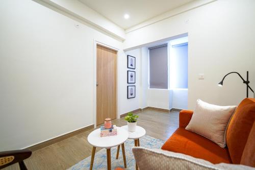 a living room with an orange couch and a table at Olive Hotel Hoodi by Embassy Group in Bengaluru