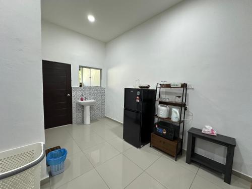 a kitchen with a black refrigerator and a sink at Homestay Taman Laksamana, Muar in Muar