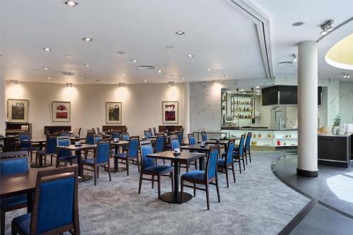 a dining room with tables and blue chairs at Radisson Blu Sobieski in Warsaw