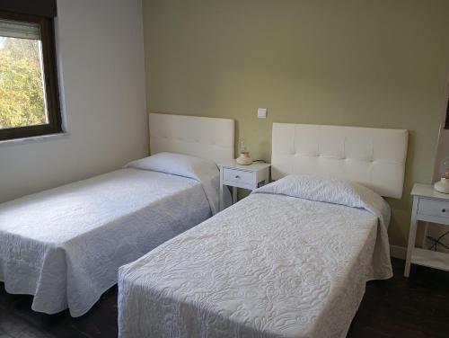 a bedroom with two beds and a window at La Casa de Pepe in Muros de Nalón