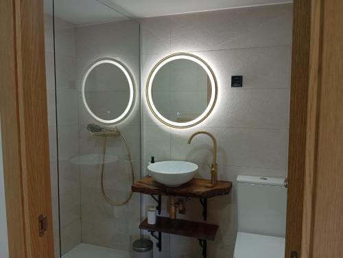 a bathroom with a sink and a shower with two windows at La Casa de Pepe in Muros de Nalón