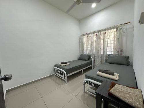 a room with two beds and a table at Homestay Taman Laksamana, Muar in Muar