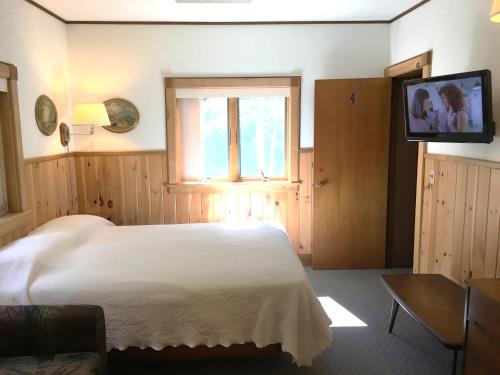 a bedroom with a white bed and a television at Slide Mountain Forest House in Oliverea