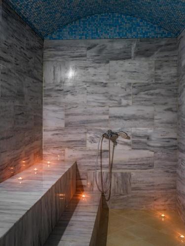 a shower in a bathroom with a stone wall at Aegean Melathron Thalasso Spa Hotel in Kallithea Halkidikis