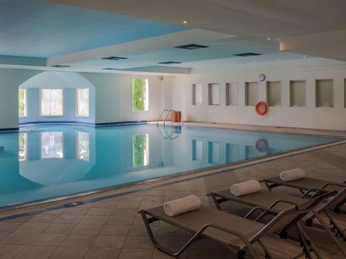 a swimming pool with chairs in the middle of it at Aegean Melathron Thalasso Spa Hotel in Kallithea Halkidikis