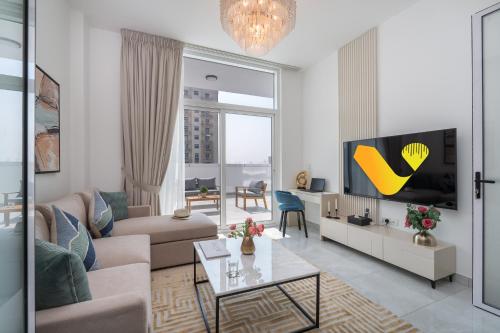 a living room with a couch and a tv at Vogue Vacation Homes, Al Furjan Pearlz by Danube near Ibn Battuta Mall, One Bedroom Apartment with Terrace and vibrant community view, Access to all Amenities, Walkable to Al Furjan Metro Station in Dubai