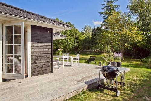 a wooden deck with a grill in a yard at 902-N-Tisvildeleje-Klovervej-9 in Tisvildeleje