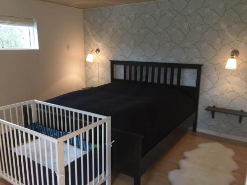 a bedroom with a black bed and a crib at 1606-Liseleje-Lisevaenget-18 in Liseleje