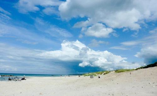 a beach with people sitting on the sand and the ocean at 1606-Liseleje-Lisevaenget-18 in Liseleje