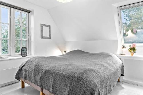 a white bedroom with a bed and two windows at 1539-Liseleje-Skippervej-3 in Liseleje
