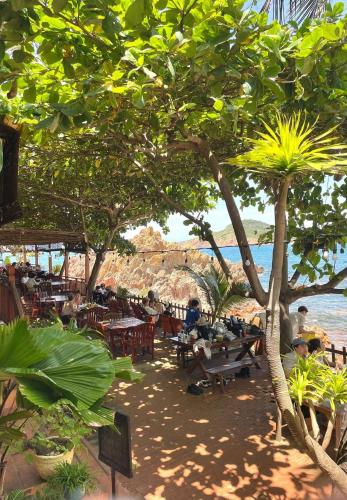 クイニョンにあるHaven Boutique Hotel Quy Nhonのテーブルと椅子と木と水のあるビーチ