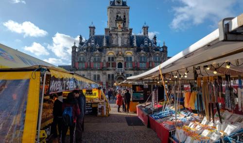 a market in front of a large building with a clock tower at Hotel La Noire - Delft City Centre in Delft