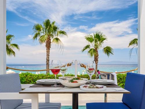 a table with glasses of wine and a view of the ocean at Aegean Melathron Thalasso Spa Hotel in Kallithea Halkidikis