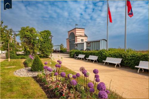 a park with benches and purple flowers in front of a building at Ferienanlage Bansin Seepferdchen 2 in Bansin