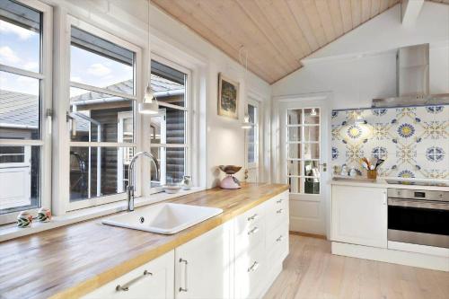 a kitchen with white cabinets and a sink and windows at 1517-Melby-Lindebjergvej-78 in Melby