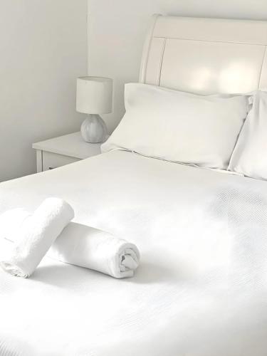 a white bed with a rolled up towel on it at Luxury Home -Private Rooms- 3 mins from Alexandra Hospital, Redditch in Studley