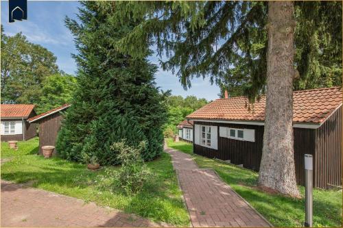 a house with a tree next to a sidewalk at Ferienanlage Bansin Seepferdchen 4 in Bansin