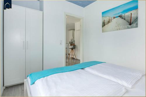 a white bedroom with a bed and a painting on the wall at Ferienanlage Bansin Seepferdchen 5 in Bansin