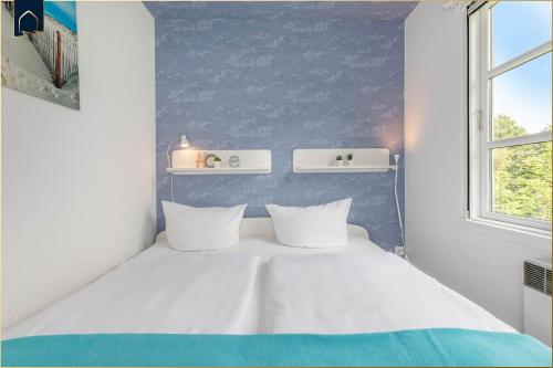 a bedroom with a white bed with a blue wall at Ferienanlage Bansin Seepferdchen 6 in Bansin