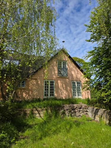 an old house with a stone wall and trees at Sandaasen Ecological Farm in Hillerød