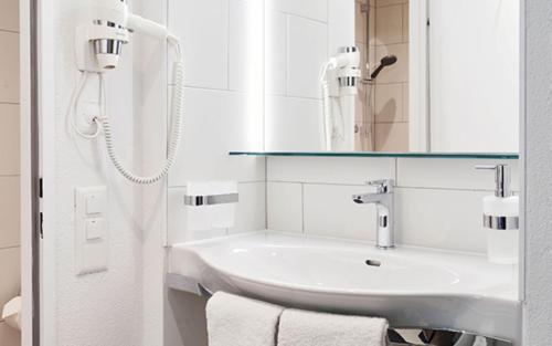 a white bathroom with a sink and a mirror at Hotel Bellinzona Sud Swiss Quality in Monte Carasso
