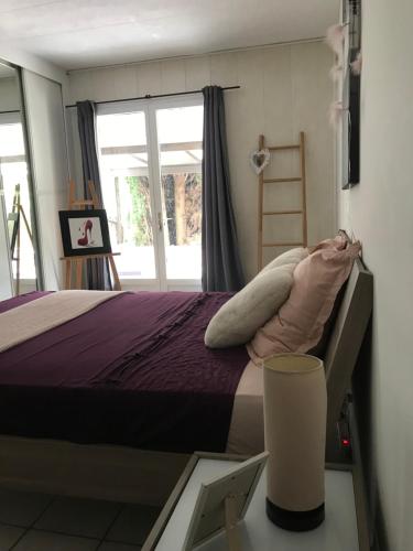 a bedroom with a bed with purple sheets and a window at Maison belle-vie in Corconne