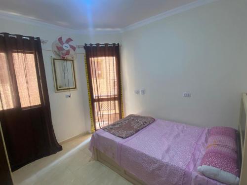 a bedroom with a purple bed and two windows at Blubay VIP in Marsa Matruh