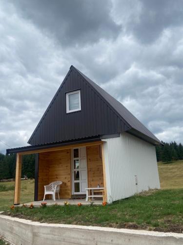 a cabin with a black roof and a chair in front at Jovovic House in Žabljak