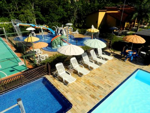 uma piscina exterior com cadeiras e guarda-sóis e um parque aquático em Hotel Bosques do Massaguaçu em Caraguatatuba
