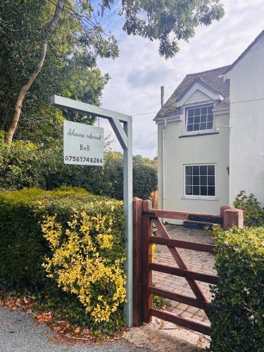 a sign in front of a house with a gate at Dolmans Retreat in Lytchett Matravers