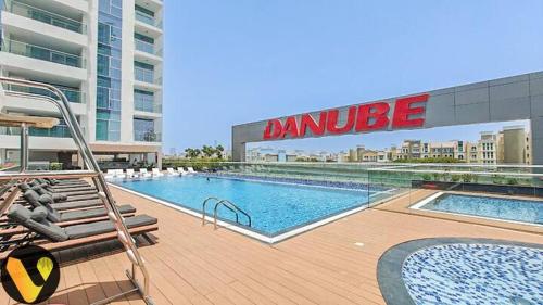 a large swimming pool on a building with a building at Vogue Vacation Homes, Al Furjan Pearlz by Danube near Ibn Battuta Mall, One Bedroom Apartment with Terrace and vibrant community view, Access to all Amenities, Walkable to Al Furjan Metro Station in Dubai