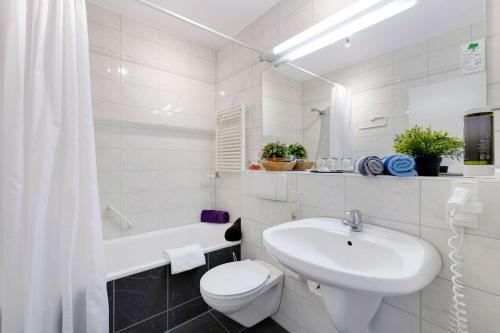 a white bathroom with a toilet and a sink at Hotel Montago- Dein großes Zimmer mit hervorragender Infrastruktur in Neu Isenburg