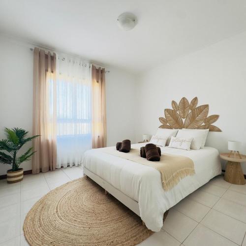 a white bedroom with a large white bed with a rug at Recanto das Areias - 2-bedroom apartment 5 minutes from the beach in Torreira