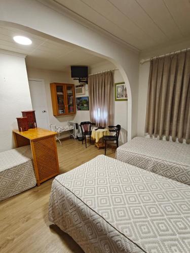 ein Hotelzimmer mit zwei Betten und einem Tisch und einem Schreibtisch in der Unterkunft Alojamiento la Casa del Brigadier in Cerro Muriano