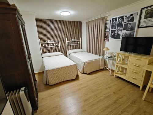 ein kleines Zimmer mit zwei Betten und einem Fernseher in der Unterkunft Alojamiento la Casa del Brigadier in Cerro Muriano