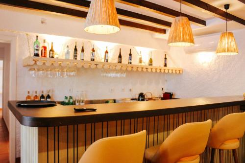 a bar with yellow chairs and bottles on the wall at Penedo Escape Nature in Colares