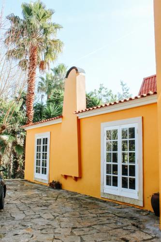 a yellow house with a palm tree in the background at Penedo Escape Nature in Colares