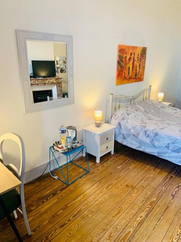 a bedroom with a bed and a table and a mirror at vaste chambre familiale in Bourg-en-Bresse