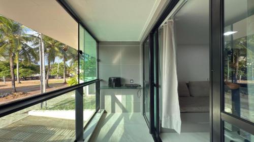 a room with glass walls and a balcony with a couch at Flat pé na areia na praia de Porto de Galinhas próximo as piscinas naturais. in Porto De Galinhas