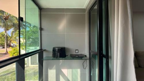 a kitchen with a glass shelf with a toaster on it at Flat pé na areia na praia de Porto de Galinhas próximo as piscinas naturais. in Porto De Galinhas