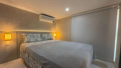 a small bedroom with a bed and two lights at Flat pé na areia na praia de Porto de Galinhas próximo as piscinas naturais. in Porto De Galinhas