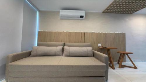 a couch sitting in a living room with a air conditioner at Flat pé na areia na praia de Porto de Galinhas próximo as piscinas naturais. in Porto De Galinhas