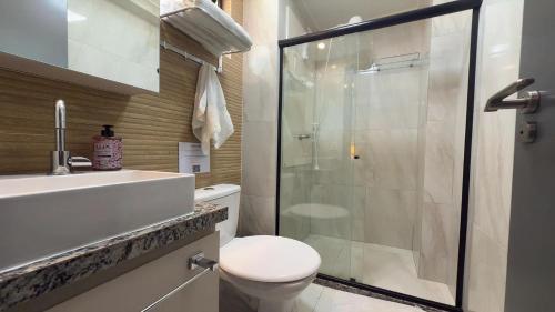a bathroom with a toilet and a glass shower at Flat pé na areia na praia de Porto de Galinhas próximo as piscinas naturais. in Porto De Galinhas