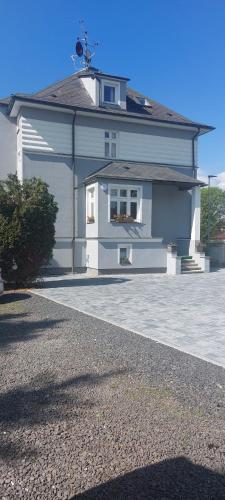 a large white house with a driveway in front of it at Apartmán Rainbow se zahradou, bazénem a parkováním in Karlovy Vary